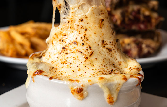 A bowl of French onion soup with golden-brown cheese, perfect for a cozy night at Carnegie Bar.
