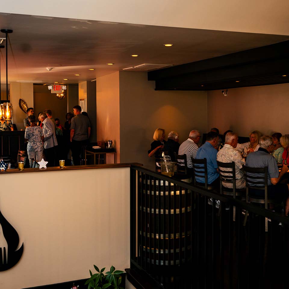 People dining and socializing at Carnegie Restaurant & Bar with modern decor and a warm atmosphere.