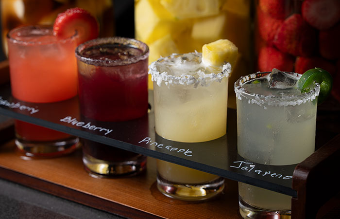 Four colorful margaritas on a tray at Carnegie Steakhouse, labeled strawberry to jalapeño.