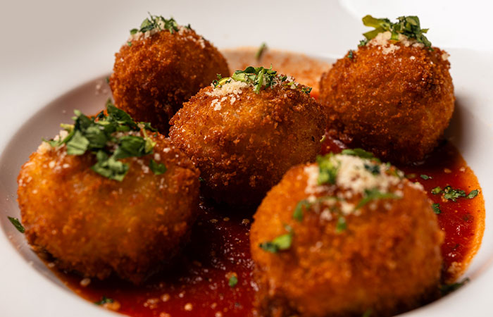 Savor Italian risotto balls at DeBlaze at 131, golden and topped with herbs and cheese.