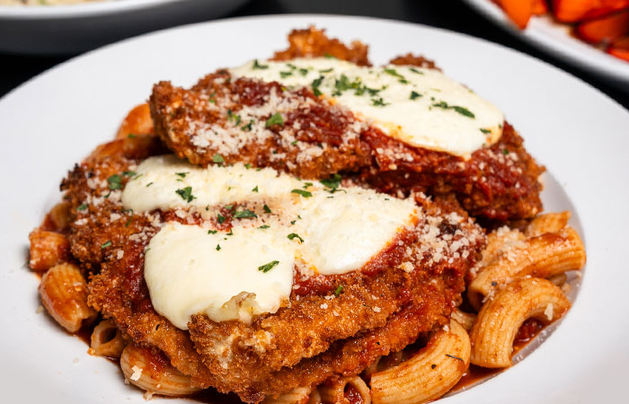 Italian-inspired breaded chicken cutlets and cheese on pasta, served at our restaurant and bar.