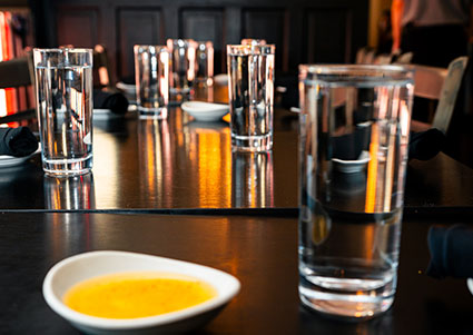 Glasses of water and a bowl of yellow sauce at DeBlaze at 131, an inviting Italian restaurant.